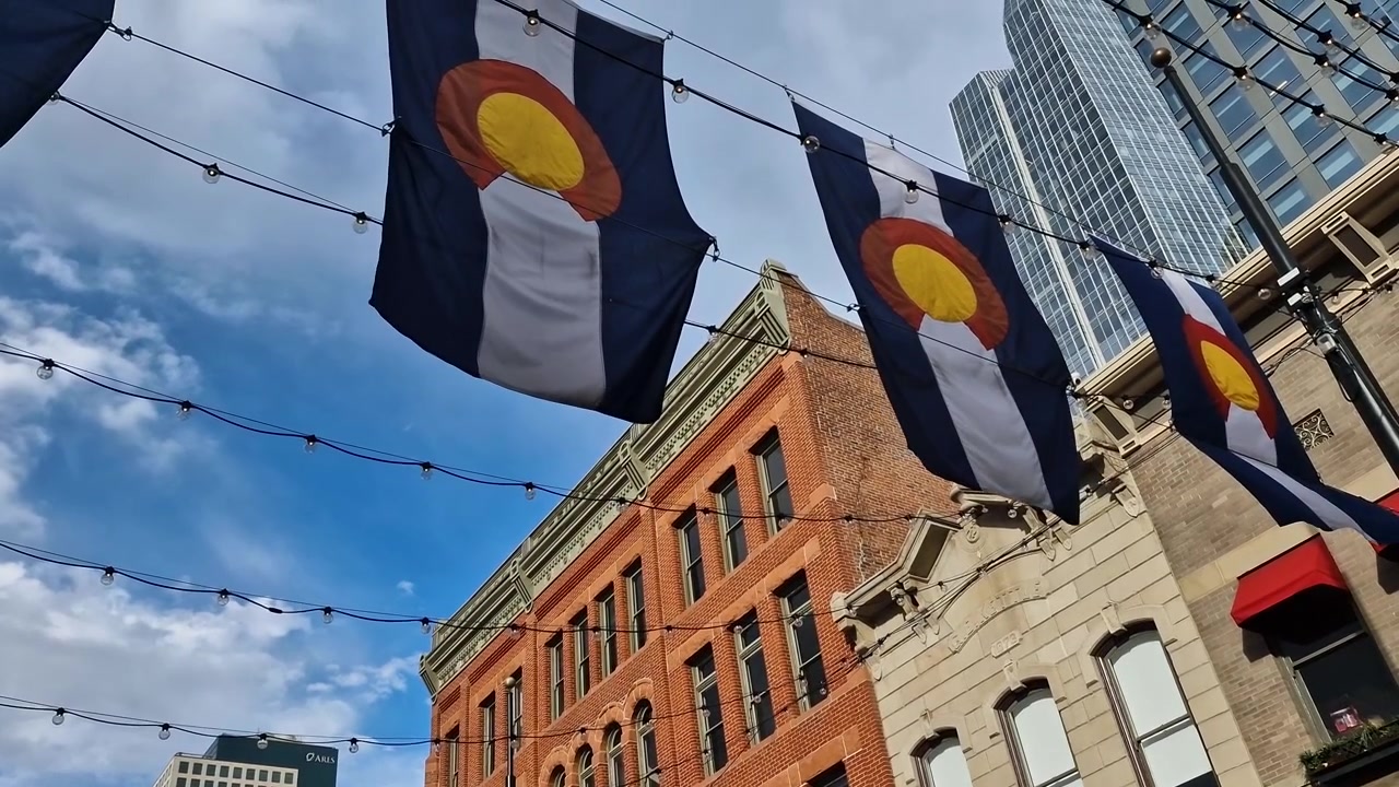 Colorado State Flags on Larimer Square Under Historic and Modern Buildings in Downtown Denver USA