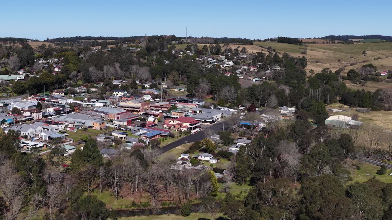 Drone ascends over Dorrigo, revealing rural town, shops, homes, roads, and surrounding countryside