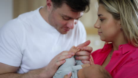 beautiful couple holding a newborn baby. loving dad kisses tiny infant's feet. close up.