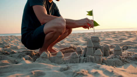 man building a sandcastle on the beach at sunset