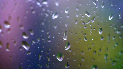 waterdruppels die op vensterglas vallen. regendruppels die afgetrokken vallen. druppels die naar beneden lopen. kleurige achtergrond.