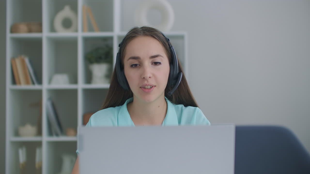 joven feliz mujer de negocios usa auriculares habla con cámara web haciendo llamada de videoconferencia en línea a distancia. maestra de internet haciendo chat a distancia trabajando desde casa. concepto de teletrabajo. vista de cámara web