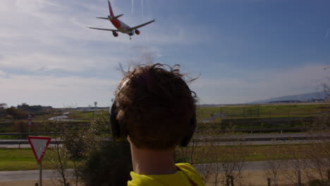 teenager watching airplane landing at airport