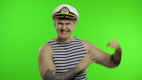 young sailor man shows muscles, looking at camera. seaman guy in sailor's vest