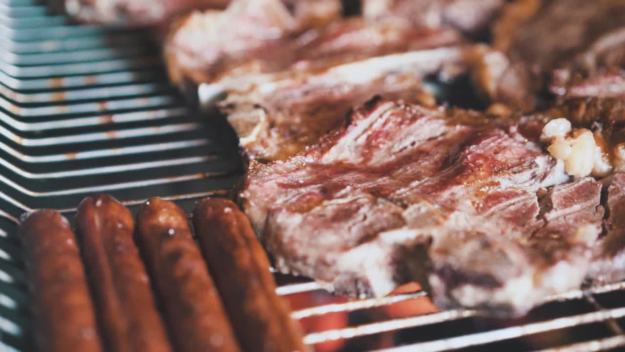 bistecs y salchichas a la parrilla barbacoa tiro cinemático cámara lenta