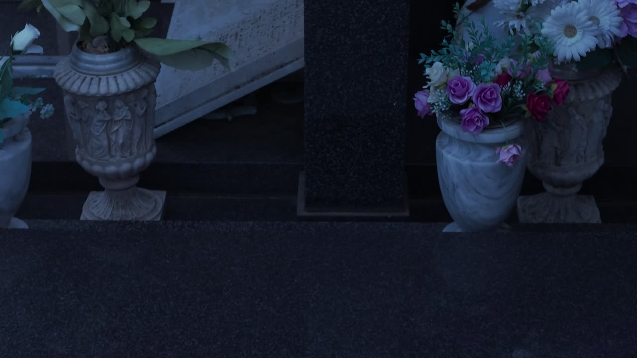 Una vista tranquilla del cimitero di Ferntree Gully al tramonto a Melbourne. Fredde lapidi di marmo proiettano lunghe ombre nella morbida luce dorata, creando una scena cupa e suggestiva.