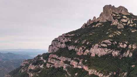 un avión no tripulado se desliza sobre los acantilados verdes de montserrat en un día tranquilo y nublado.