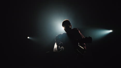 a young musician plays the guitar on the stage in the spotlight 4k video