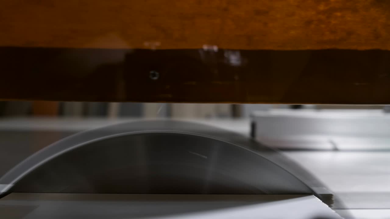 POV: Kreissäge sägt Brett. Nahaufnahme einer Tischkreissäge beim Schneiden eines Brettes.