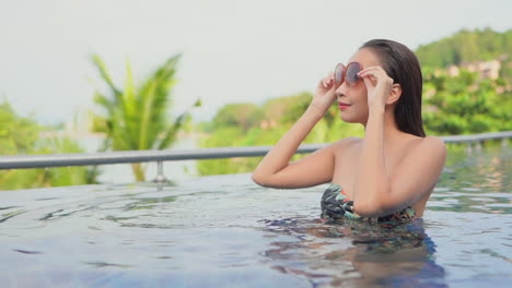 fashionable woman in pool with tropical background