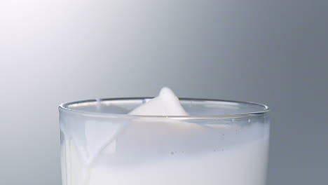 a cookie falls into a glass of milk and splashes a lot