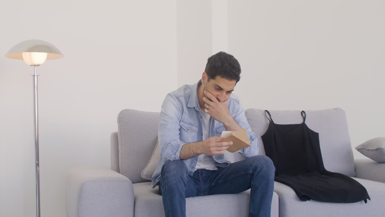 un hombre de cabello oscuro se enoja y se frustra después de leer una carta, así que la rompe