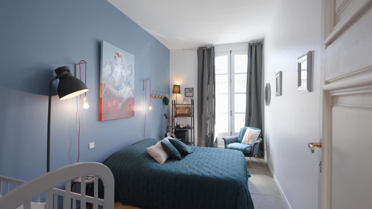 Slow establishing shot of a master bedroom with a babies cot in the corner