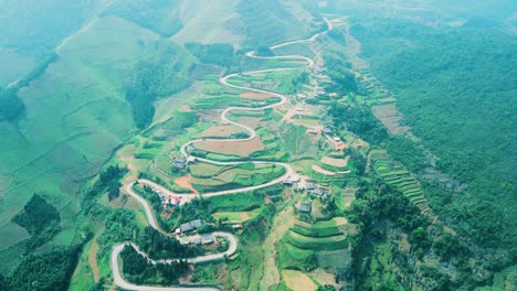 Stunning-switchback-hairpin-road-zig-zagging-and-weaving-meandering-through-green-patchwork-hillside-of-northern-Vietnam