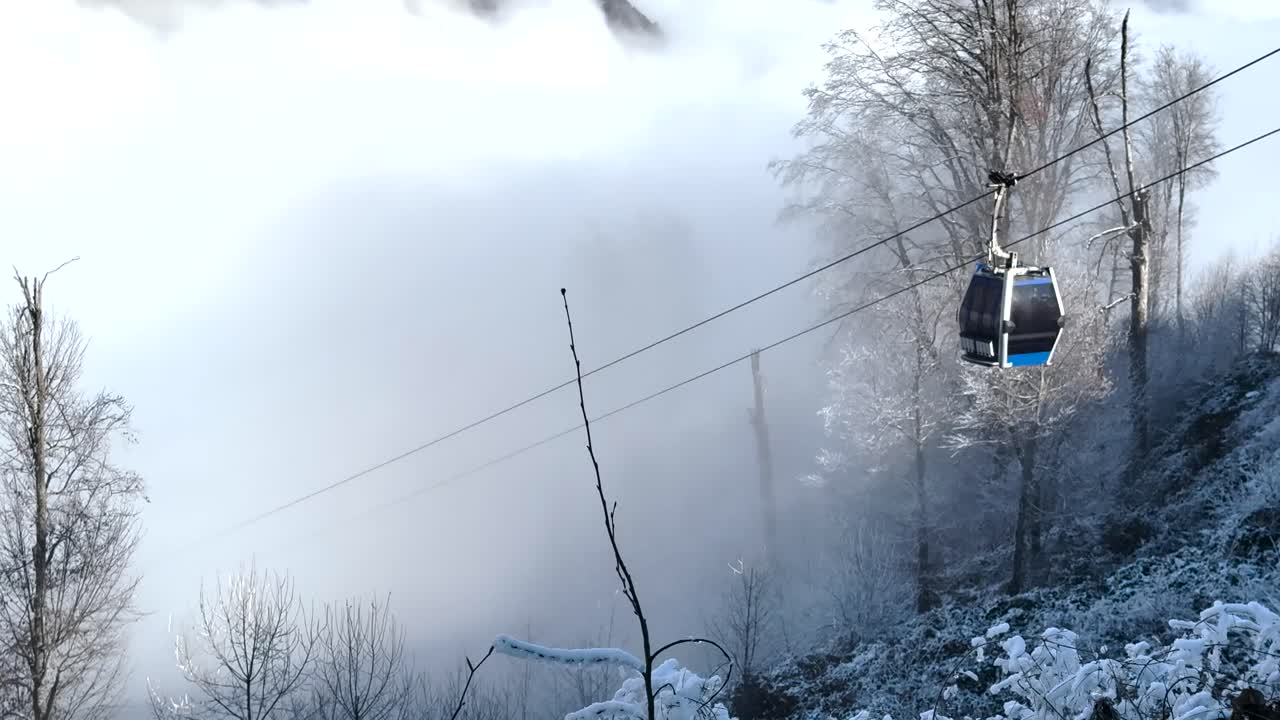 Chair lift moves through misty, snow-covered forest in the mountains of Gebele. Gebele, Azerbaijan