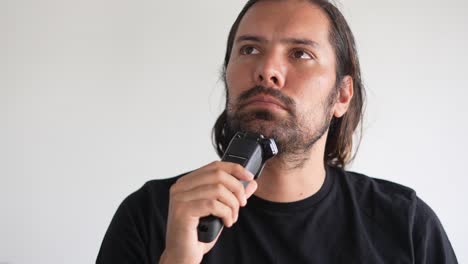 hombre latino recortando barba y bigote con afeitadora eléctrica, loción para después de afeitarse