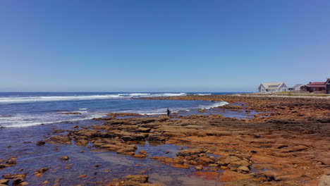 Sudáfrica-Drone-Aéreo-Cinemático-Surfista-Mirando-Las-Olas-De-Pie-En-El-Arrecife-Listo-Para-Remar-En-La-Tabla-De-Surf-Todavía-Bae-Ruta-Del-Jardín-Jeffreys-Bay-Luz-Del-Día-A-última-Hora-De-La-Mañana-Surf-De-Verano