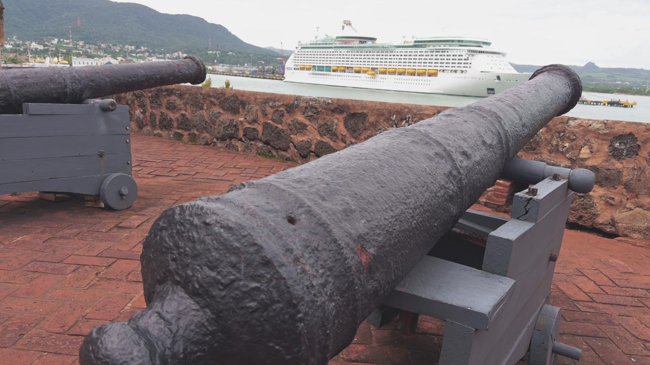 Two antique cannons at Fortaleza San Felipe overlooking the port with a modern cruise ship, contrasting old and new in Puerto Plata, Dominican Republic