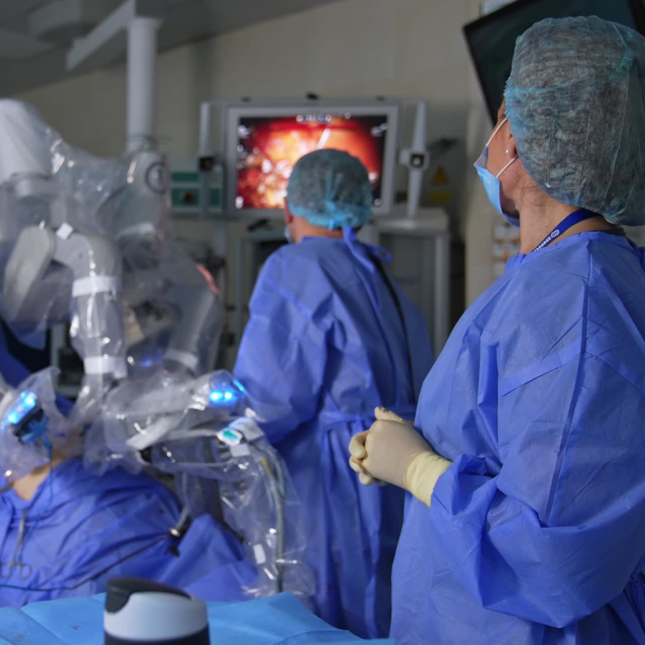 Surgeon and nurse are focused on the screen showing the procedure progress. Modern robotic equipment conducting operation