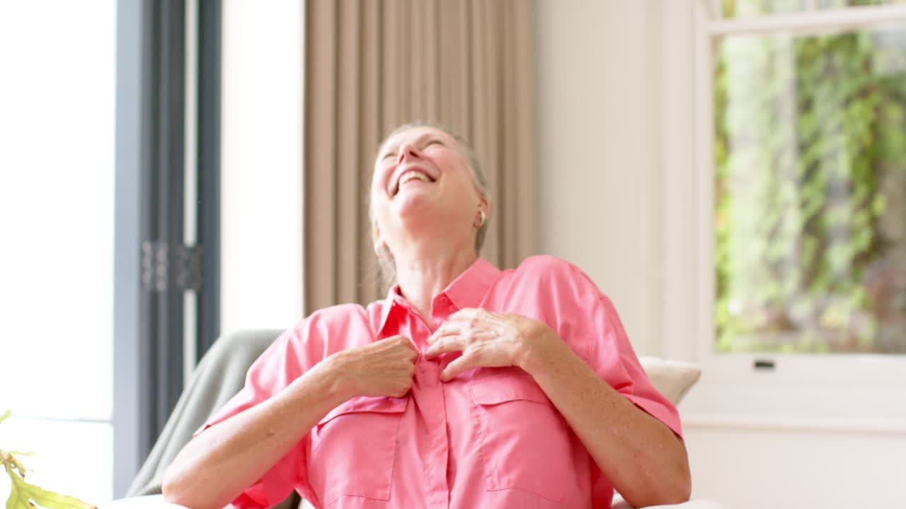 고령의 즐거운 백인 여성이 실내에서 비디오 통화에서 웃고 있습니다.