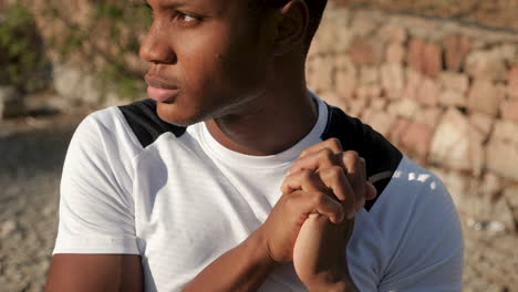 portrait of young black man warming up wrists and arms before running outdoors