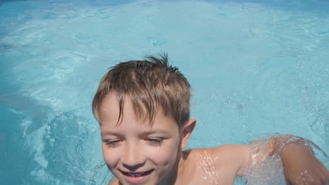 Lächelnder-Junge-Schwimmt-Auf-Die-Kamera-Zu,-Kaukasisches-Kind-Schaut-Und-Lächelt-In-Die-Kamera