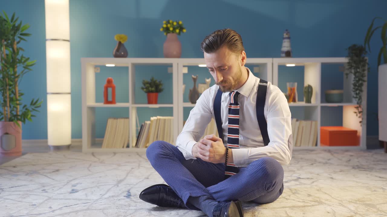 hombre carismático y guapo sentado solo en el suelo de su casa y pensando. ideas creativas, el deseo de tener éxito.