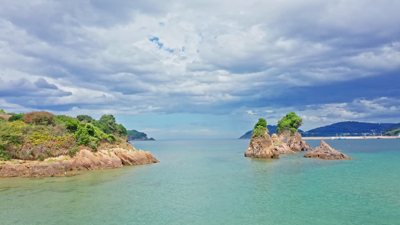 공중 최고 수준의 드론이 스페인 북부 갈리시아의 해변 위를 날고, 갈매기는 맑은 바닷물 위를 날고 있습니다.