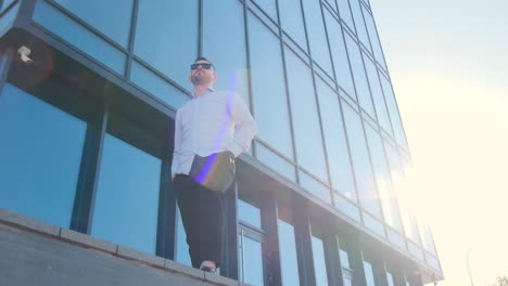 serious young confident successful asian businessman looking at camera standing near modern office