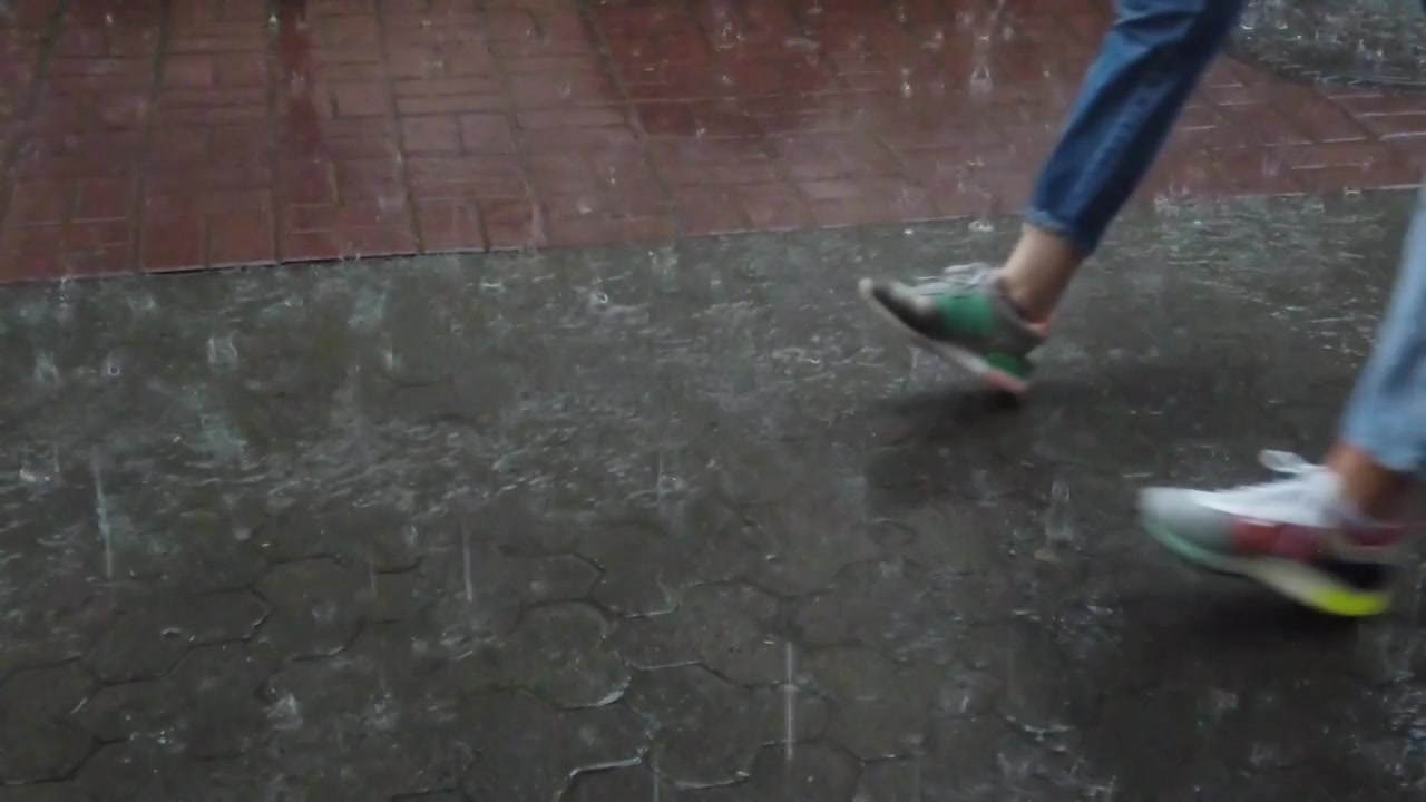Rain in the city. Rain drops fall on the sidewalk.
