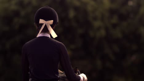 horseback riding female jockey, silk ribbon on horse rider cap, cinematic slow motion, slomo shot, forest