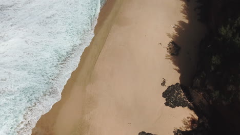 Drone-shot-of-waves-on-exotic-beach-with-sand-and-rocks,-Kauai,-Hawaii