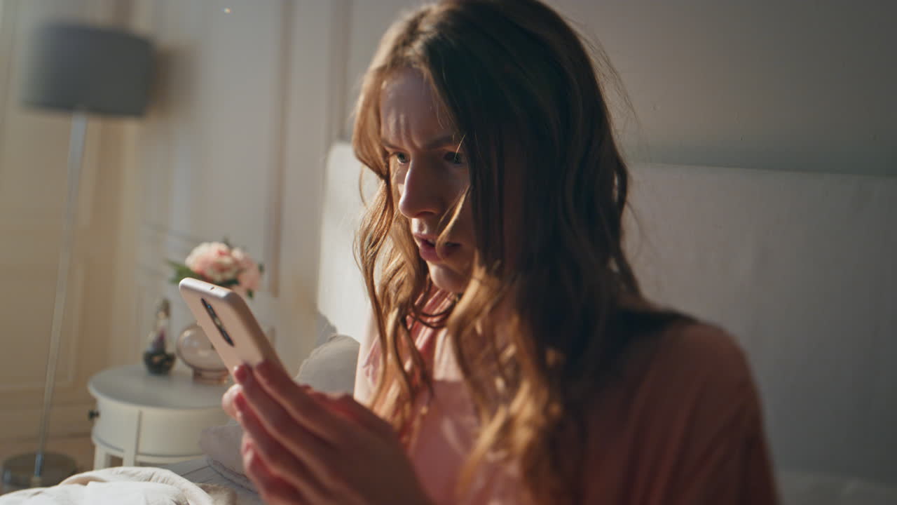 Frustrated girl looking mobile in morning closeup. Stressed sleepy female using