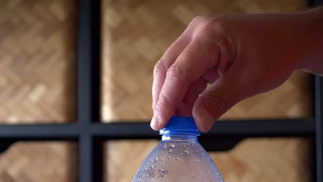 abrir la tapa azul de la mano de la botella de plástico de agua en cámara lenta