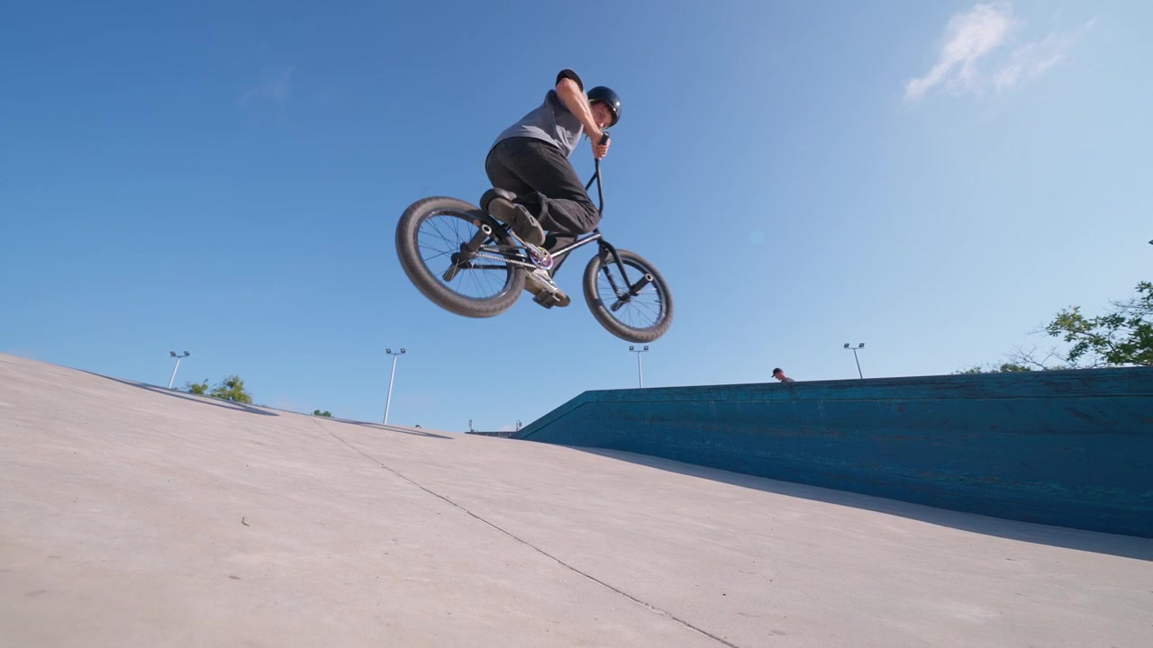 Giovane uomo in bici BMX che esegue un salto in uno skatepark