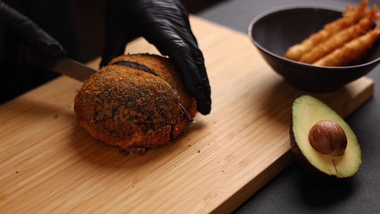 Chef che affetta un grande rotolo di sushi fritto su un tagliere di legno