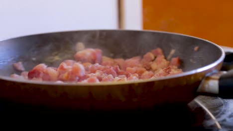 bacon is cooked and stirred in a frying pan