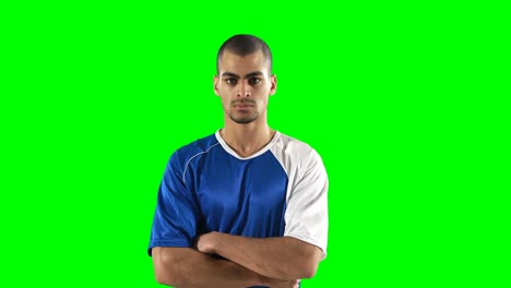 Confident-football-player-standing-against-green-screen