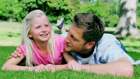 padre hablando con su hija sonriente antes de mirar a la cámara y sonriendo