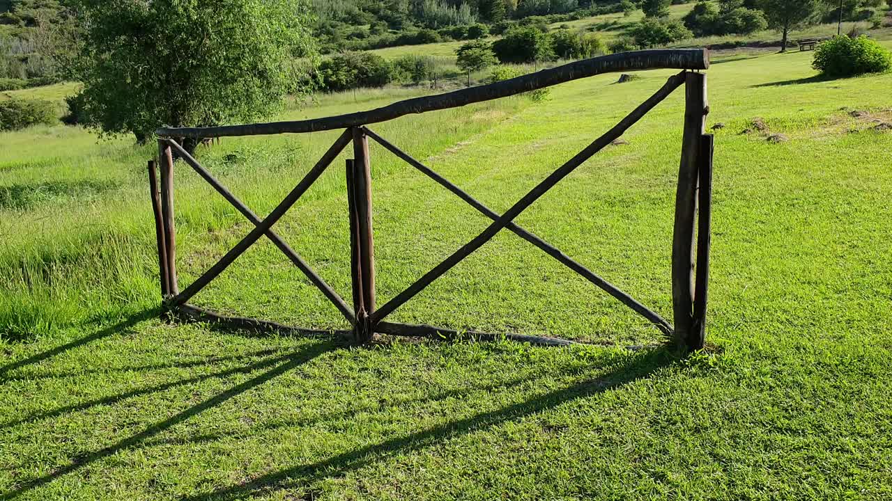 Camelroc guest farm wooden fence and green grass slowly moving up over fence to show the sandstone cliff mountains