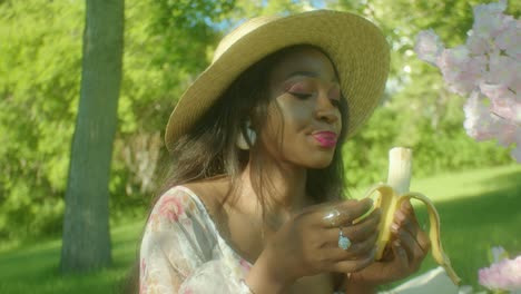 black woman eating banana chewing in park dolly in close up