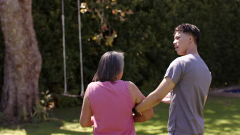 helping senior woman walk, male physiotherapist supporting her in garden