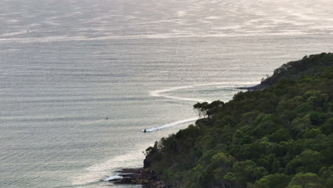 Vista-De-Aviones-No-Tripulados-De-Jetski-En-El-Océano-Alrededor-Del-Promontorio-De-Noosa-Mainbeach-Al-Amanecer,-4k-Cámara-Lenta-Australia