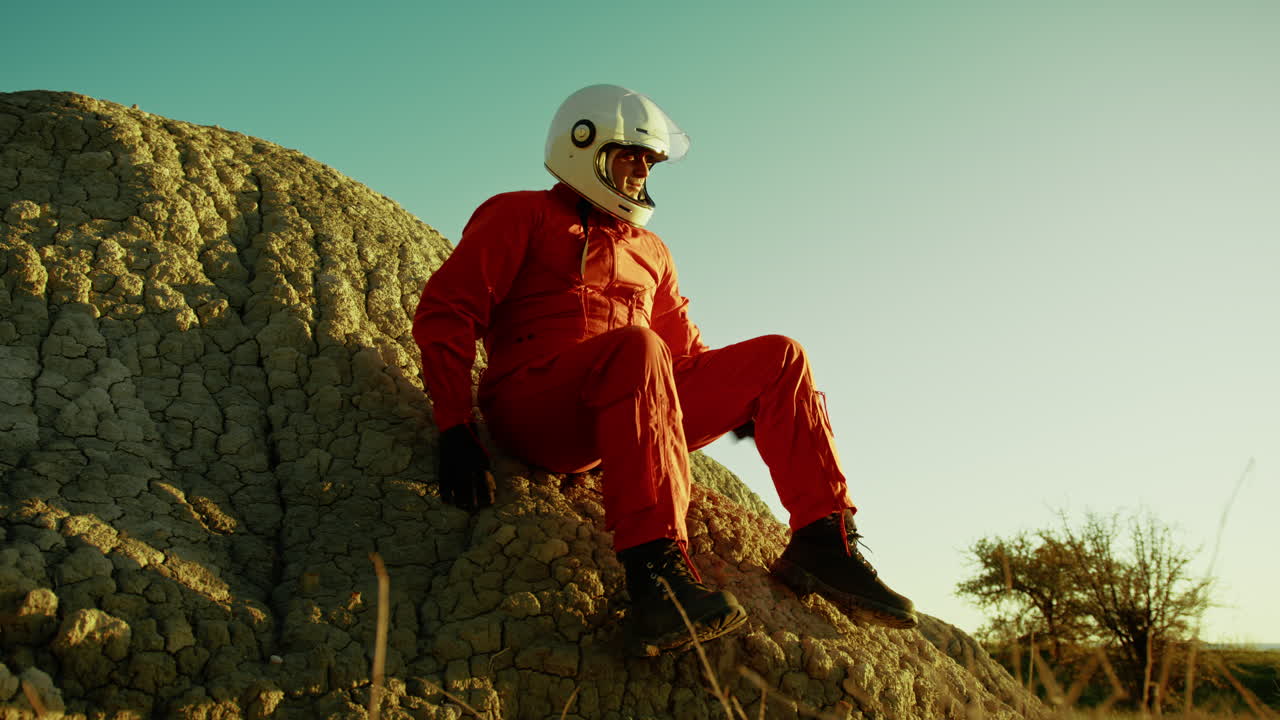 우주 비행사가 바위 위에 앉아 지구의 미래에 대해 생각하고 있습니다.