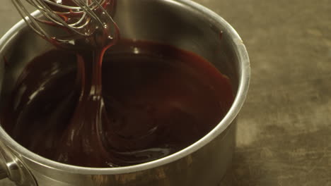 primer plano de chocolate líquido en un cuenco mezclando con un batidor en cámara lenta.