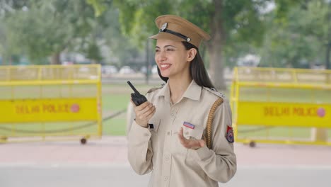 Happy-Indian-female-police-officer-talking-on-walkie-talkie