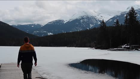 man walking out toward frozen lake in british columbia, canada