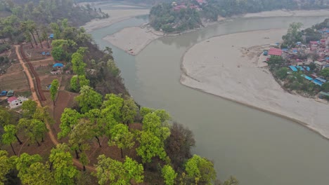 drone footage captures the peaceful landscape of devdaha in chitwan, nepal, showcasing farmlands, rural homes, and surrounding greenery under the vast sky — a glimpse into quiet nepali village life