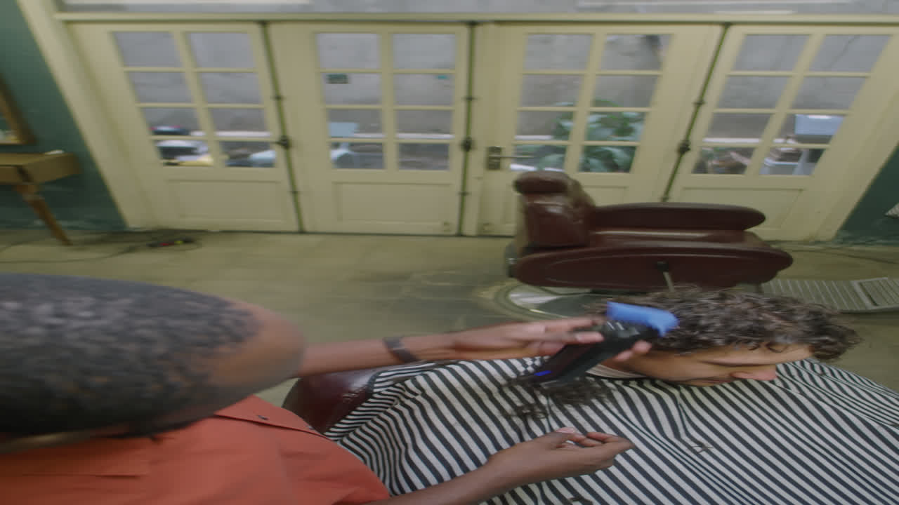 Hairdresser Trimming Hair of Client in Barbershop