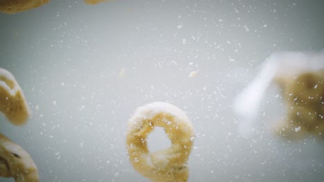 crumbly crackers fall on a transparent glass directly in front of camera